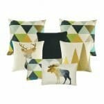 two patterned cushion in gold, black and grey, a plain black cushion, 1 moose square cushion, one rectangular cushion with triangular design, one gold and white mountain peak printed cushion and one rectangular cushion with moose print.