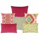 Three multi patterned cushion in fuchsia and yellow colours. Two cushion with diamond and leaf designs. One plain fuchsia cushion, one fur yellow cushion and one plain rectangular cushion in fuchsia colour.