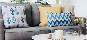 Patterned cushion in blue and yellow gives the grey sofa a pop of color that it needed.