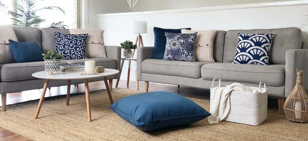 Living room decorated with different kinds of cushions in navy blue and cream colours.