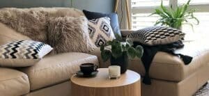 5 Pieces of white and grey fur and patterned cushions on a sofa.