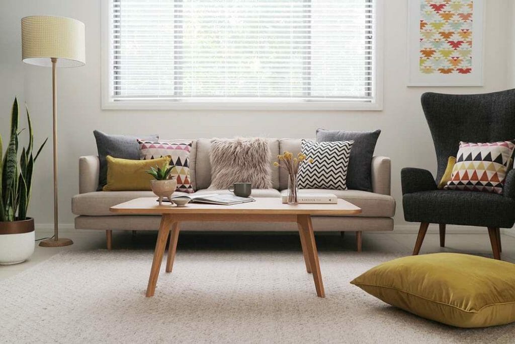 A contemporary style sofa with different patterned cushions along with a grey fur cushion and a mustard floor cushion