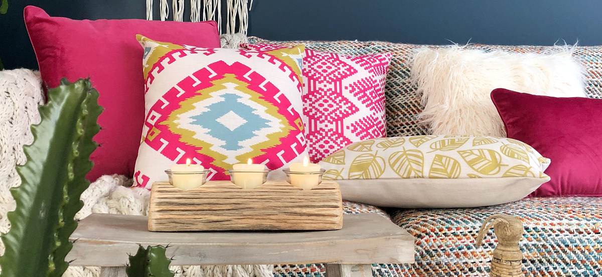 Colorful sofa with boho patterned cushions in different hues of pink.