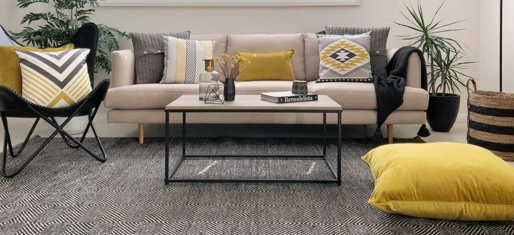 Patterned cushions in mustard and grey and a floor cushion is used to give the room a homier vibe.