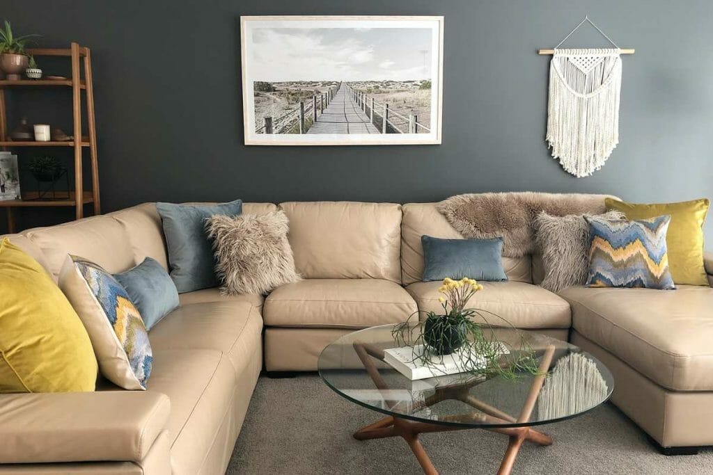 A corner sofa with decorative cushion in multiple texture and patterns in light blue and mustard colours.