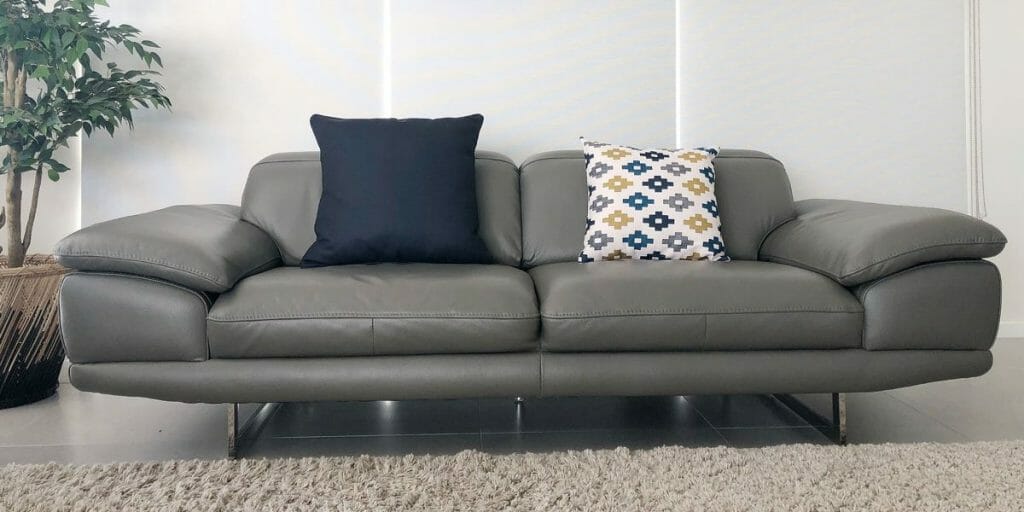 A grey sofa is decorated with a navy blue cushion and a patterned cushion to add a bit of color.