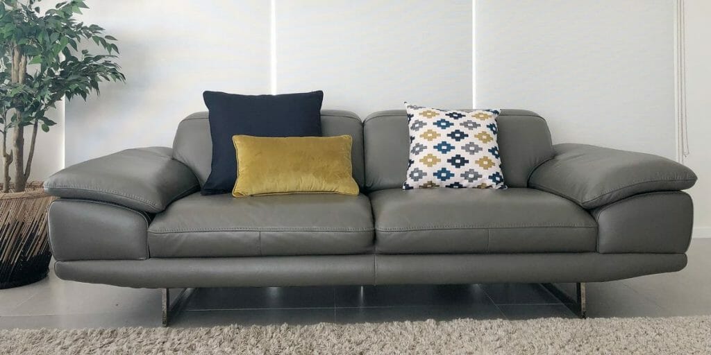 Cushions in navy blue and mustard along with a patterned cushion adorns the grey leather sofa.