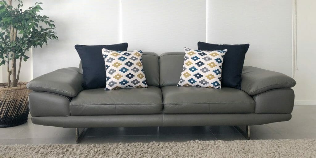 A grey sofa is decorated in pairs of navy and a patterned cushions to bring character to the sofa.