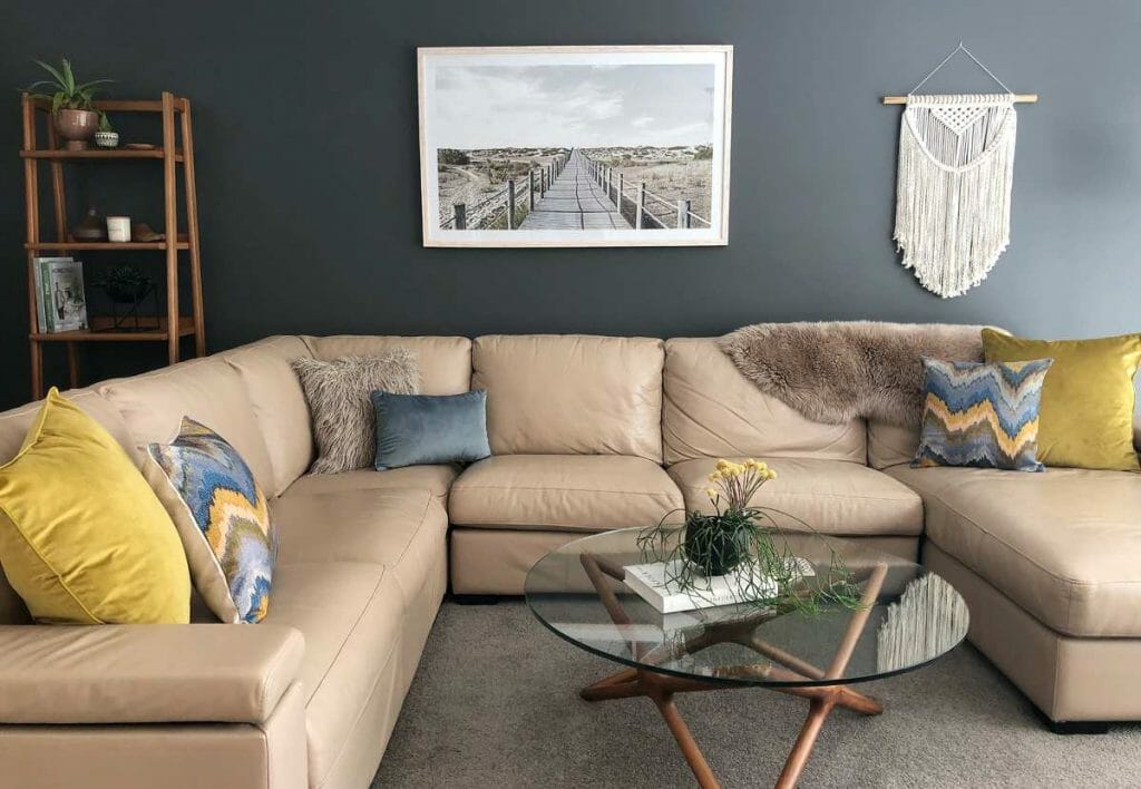 This warm and inviting sofa is decorated with mustard and blue cushions, along with some patterned cushion to give a homier vibe.