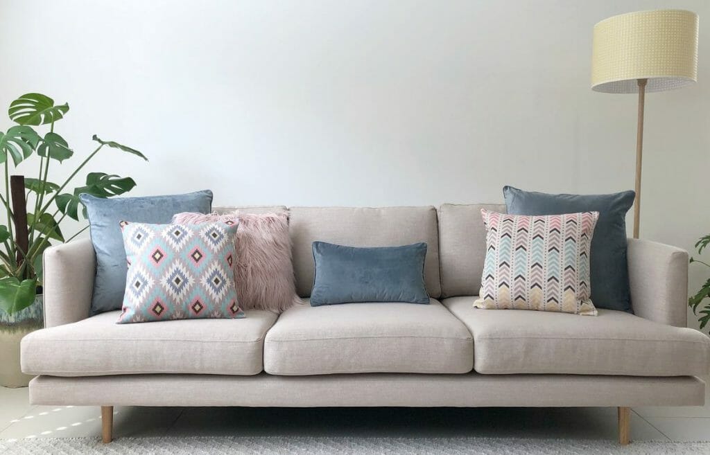 Soft grey sofa decorated with patterned cushions, along with a velvet and faux fur cushions to add a little texture, all in pastel colours.