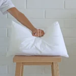 A 30x50 cushion insert inner being pressed by a hand.
