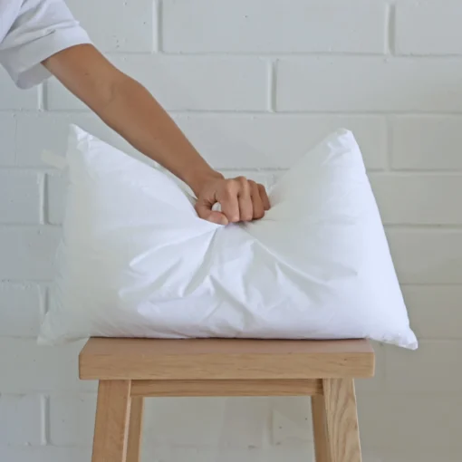 A 30x50 cushion insert inner being pressed by a hand.
