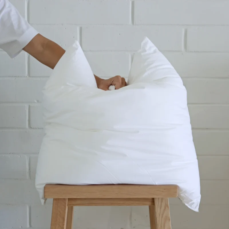 A 45x45 cushion insert inner being pressed down by a hand.