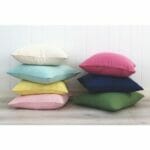 Stack of colourful linen cushions against a wall