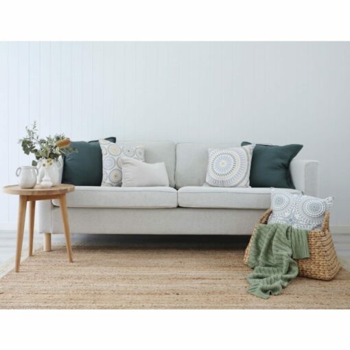 White living room with wicker basket, wooden side table, woven carpet, dark green and mandala-print cushions