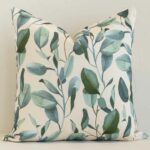 A brick wall that has a floral white cushion cover positioned in front of it. It has an exquisite outdoor material and a lovely square shape.
