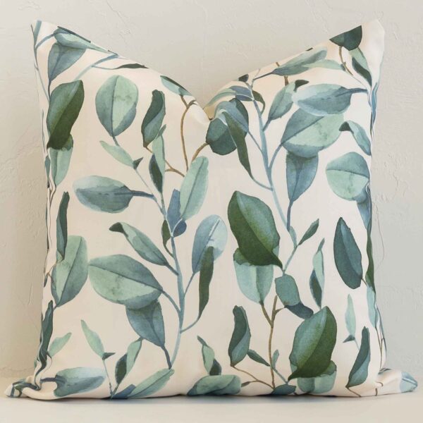 A brick wall that has a floral white cushion cover positioned in front of it. It has an exquisite outdoor material and a lovely square shape.