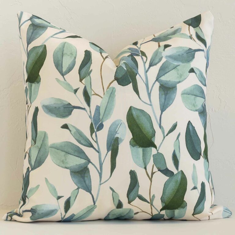 A brick wall that has a floral white cushion cover positioned in front of it. It has an exquisite outdoor material and a lovely square shape.