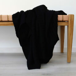 An image of a black knitted throw draped over a stool