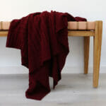 An image of a burgundy knitted throw draped over a stool