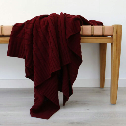 An image of a burgundy knitted throw draped over a stool