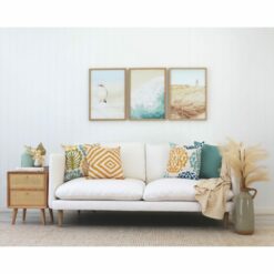 Coastal inspired cushions and wall art against a white wall and white sofa