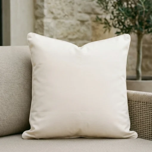 Cream Waterproof Cushion Cover v2 Cream outdoor cushion in soft beige on fabric sofa with neutral backdrop.
