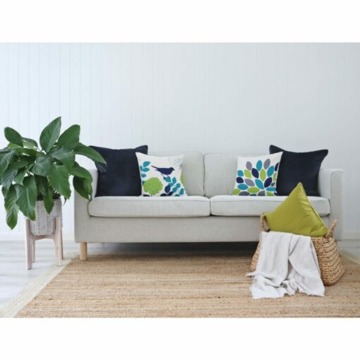 White living room with off-white sofa, indoor plant, wicker basket, woven rug and cushions in lime, teal and navy colours