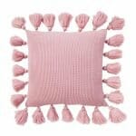 Close up image of pink knitted cushion with tassels