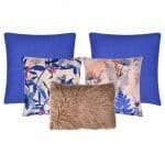An image of two blue cushions, two blue floral design cushions and a single dusty pink faux fur cushion.
