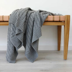 An image of a grey knitted throw draped over a stool
