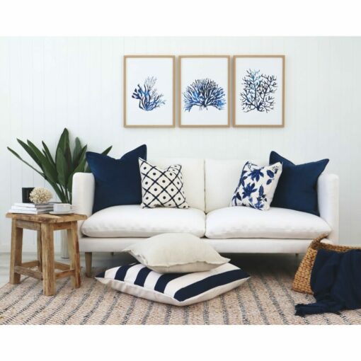 Hamptons-themed navy and white cushions against a white wall and wall art