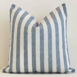 Blue stripe cushion cover in front of a white wall. It has a square size and is made from a outdoor material.