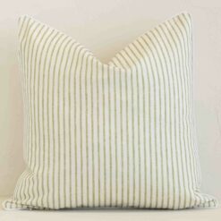 Outdoor square cushion with a stripe design in an upright position against a white brick wall. It is sage in colour.
