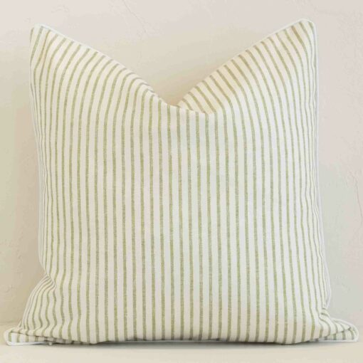 Outdoor square cushion with a stripe design in an upright position against a white brick wall. It is sage in colour.