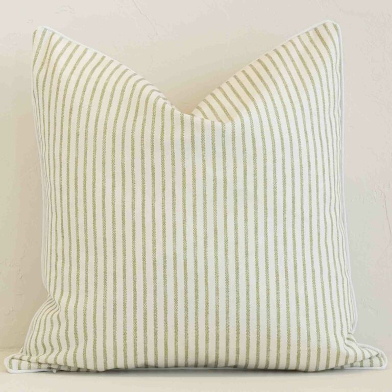 Outdoor square cushion with a stripe design in an upright position against a white brick wall. It is sage in colour.