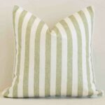 Sage outdoor cushion cover features prominently against a white wall. It is a square design and has a stripe decorative finish.
