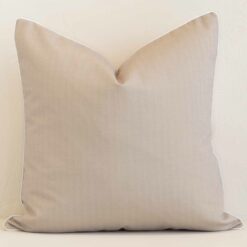 A lovely large sand cushion cover arranged in front of a white wall. The solid-colour style complements the outdoor material.