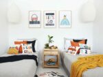 Kids bedroom with car kids cushions on twin beds with a throw blanket. On the wall are three kids wall prints that match the cushions