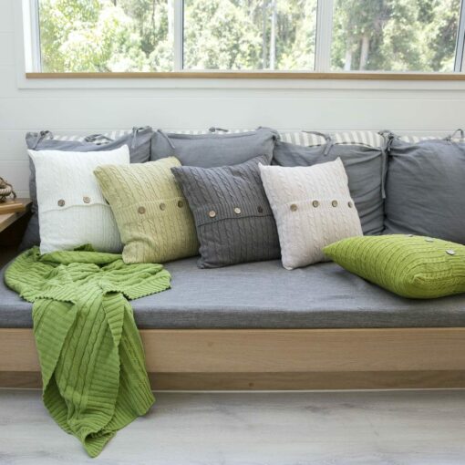 A set of knit cushions and throw blanket with natural colours arranged in grey sofa