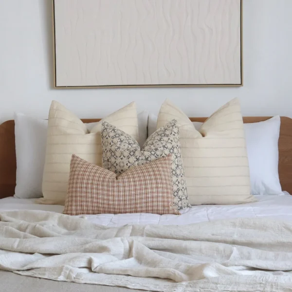 A bed with a wooden headboard adorned with the Lennox bed set of 4 designer cushions.