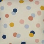Close up photo of square kids cushion with pastel polka dots