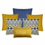 An image of one blue cushion cover, two square gold cushion covers, two blue and yellow aztec design cushion covers and a single gold velvet rectangular cushion.