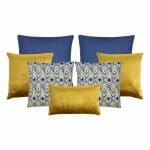 A collection of seven cushion covers featuring two blue cushions, three gold cushions and two chevron design cushions.