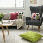 Neutral-coloured living room chairs with colourful cushions and wall accent