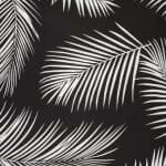 A close up of a water resistant black and white outdoor cushion cover that has a beautiful palm tree leaf print.