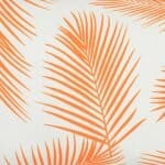 A close up view of a lovely outdoor cushion with palm tree orange print on a white background.