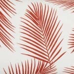 A close up view of a lovely outdoor cushion with palm tree red print on a white background.