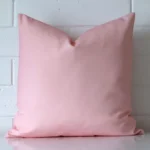 Front view of a square cushion. Crafted from a special outdoor material in a pink colour.