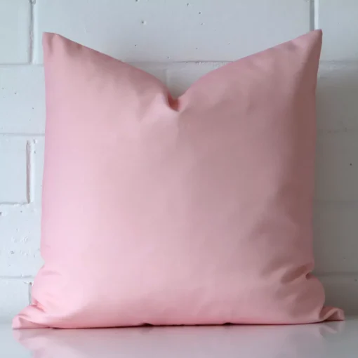 Front view of a square cushion. Crafted from a special outdoor material in a pink colour.